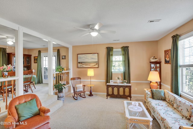 living area with visible vents, a textured ceiling, carpet flooring, and a ceiling fan