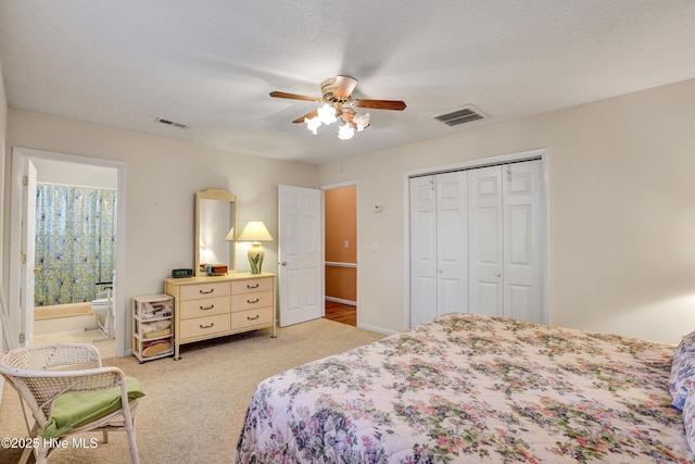 bedroom with a closet, visible vents, light colored carpet, and a textured ceiling