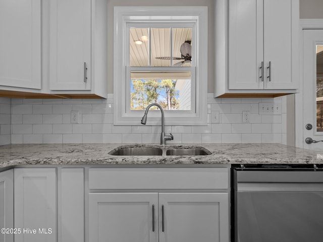 kitchen featuring a sink, backsplash, white cabinets, and light stone countertops