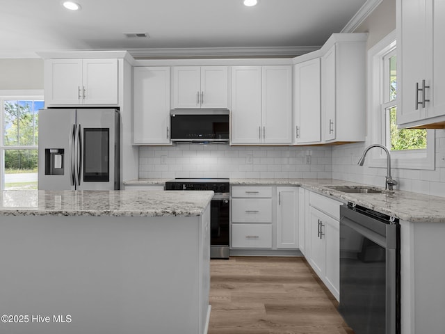 kitchen featuring crown molding, light wood-type flooring, white cabinetry, a sink, and stainless steel appliances