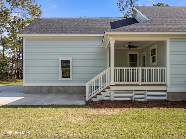 doorway to property featuring a patio area, a ceiling fan, a lawn, and roof with shingles