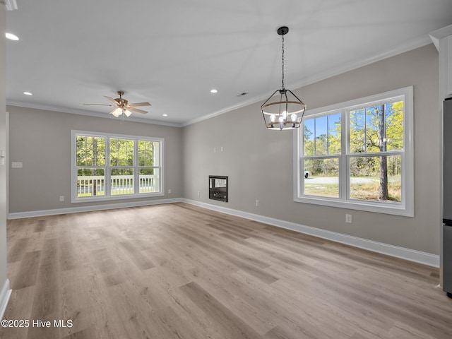 unfurnished living room featuring plenty of natural light, baseboards, and ornamental molding