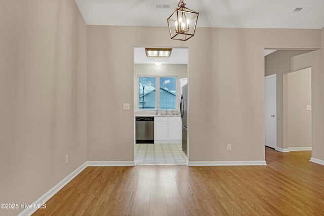 spare room featuring sink, an inviting chandelier, and light hardwood / wood-style flooring