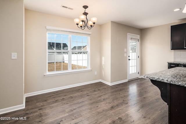 dining space featuring dark wood-type flooring and an inviting chandelier