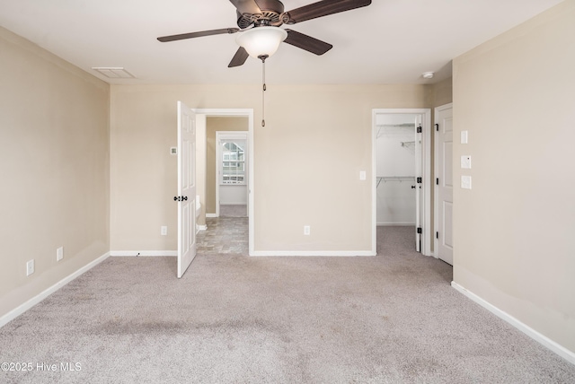 unfurnished bedroom featuring ceiling fan, a spacious closet, light carpet, and a closet