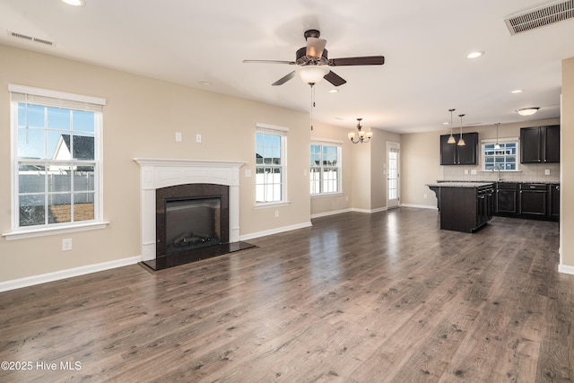 unfurnished living room with ceiling fan with notable chandelier, dark hardwood / wood-style flooring, and sink