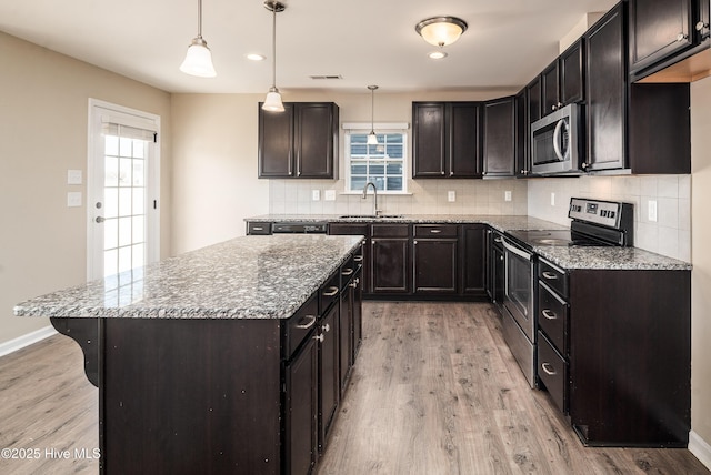 kitchen with a kitchen island, stainless steel appliances, hanging light fixtures, and light hardwood / wood-style flooring