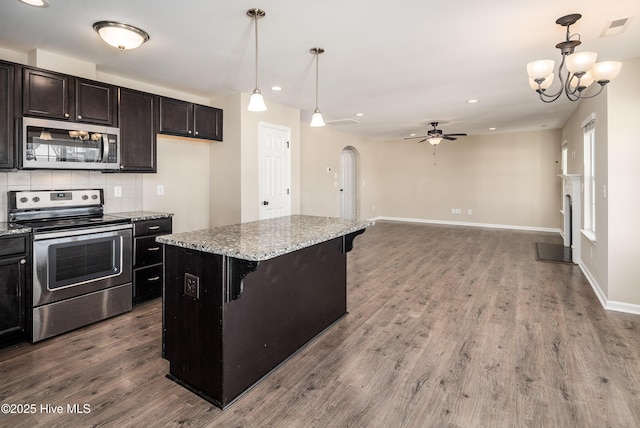 kitchen featuring stainless steel appliances, pendant lighting, a breakfast bar area, a kitchen island, and ceiling fan with notable chandelier