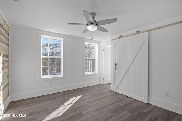 interior space with dark hardwood / wood-style flooring, a barn door, and ceiling fan