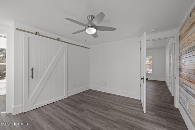 interior space featuring crown molding, dark hardwood / wood-style flooring, a barn door, and ceiling fan