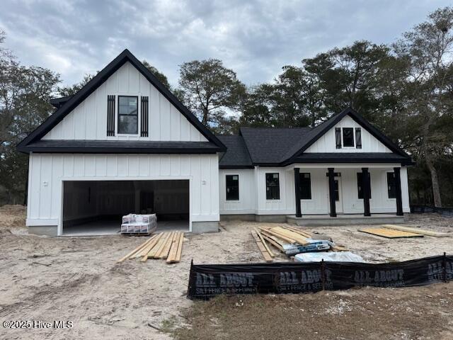 back of property with covered porch and a garage