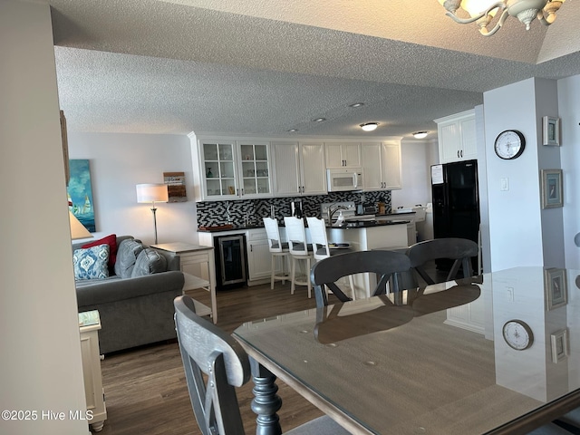 dining space with sink, wine cooler, dark hardwood / wood-style floors, a textured ceiling, and a chandelier