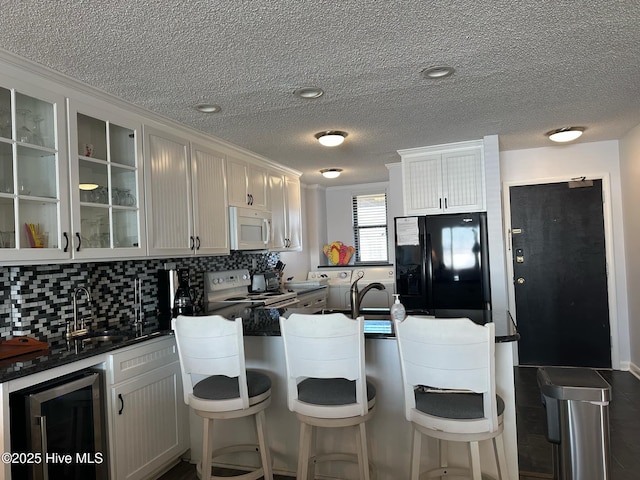 kitchen featuring white cabinetry, sink, beverage cooler, and white appliances