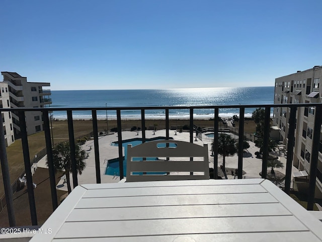 balcony with a water view and a view of the beach