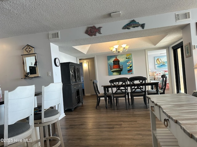 dining space with dark wood-type flooring, a textured ceiling, and a notable chandelier