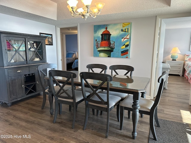 dining room with dark hardwood / wood-style flooring, a textured ceiling, and a chandelier