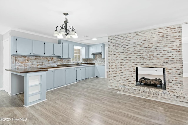 kitchen featuring butcher block counters, decorative light fixtures, an inviting chandelier, light hardwood / wood-style flooring, and backsplash