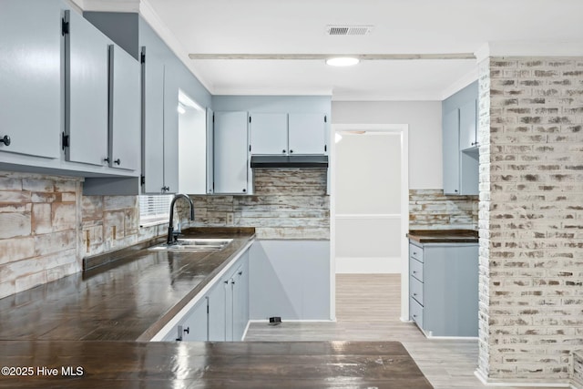 kitchen featuring sink, crown molding, tasteful backsplash, and gray cabinetry