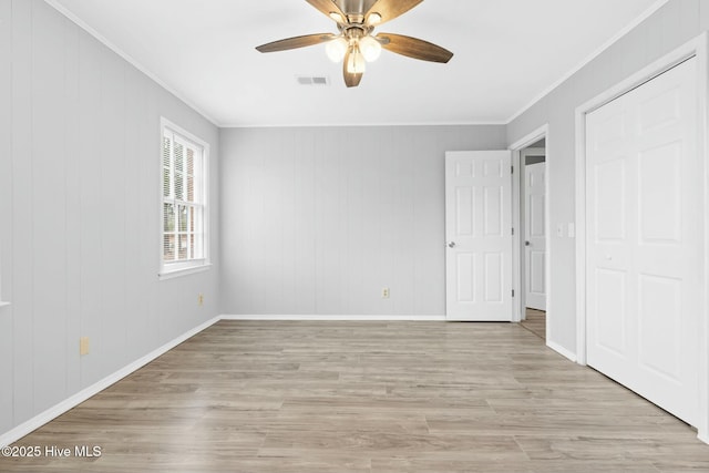 unfurnished bedroom featuring wooden walls, ceiling fan, light hardwood / wood-style floors, and ornamental molding