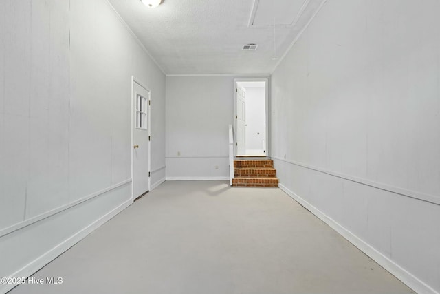 empty room with a textured ceiling and ornamental molding