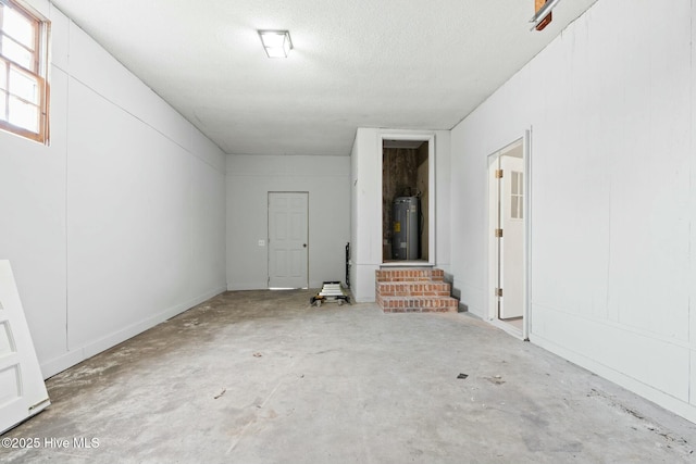 interior space with electric water heater and concrete flooring