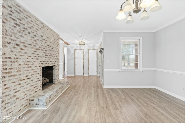 unfurnished living room featuring a fireplace, a chandelier, crown molding, and light hardwood / wood-style flooring