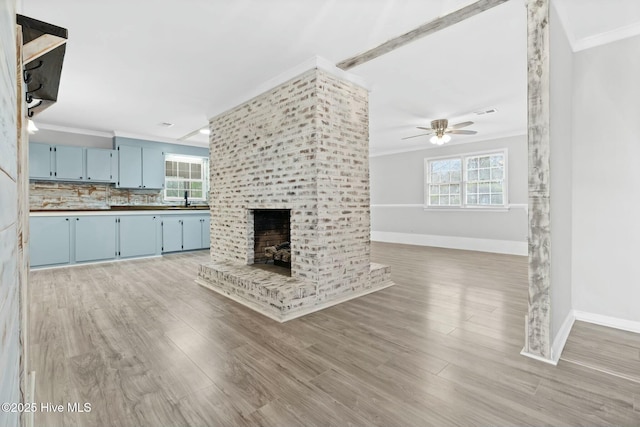 unfurnished living room with ornamental molding, ceiling fan, a healthy amount of sunlight, and a fireplace