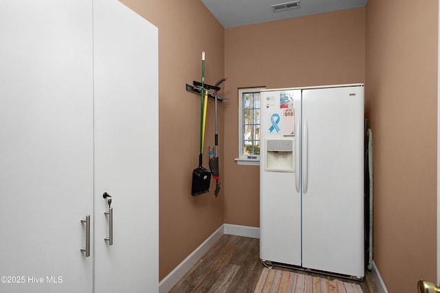 kitchen with baseboards, white fridge with ice dispenser, visible vents, and wood finished floors