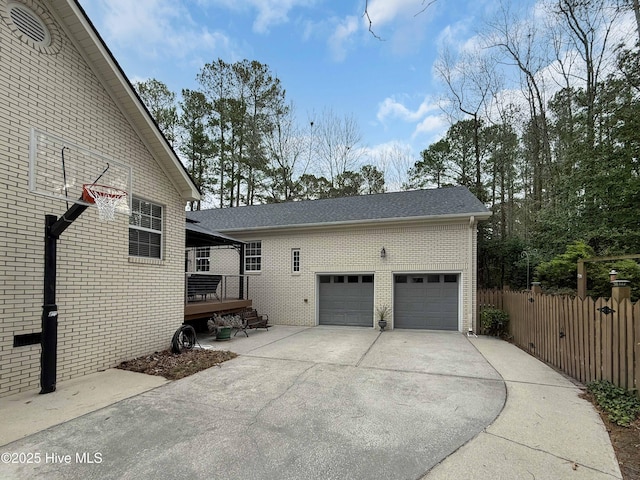 view of property exterior featuring driveway, brick siding, and fence