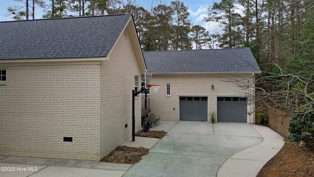 view of home's exterior with a garage, driveway, brick siding, and a shingled roof