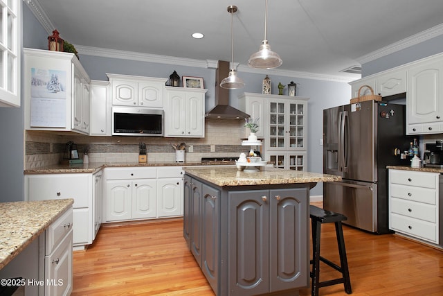 kitchen with a kitchen breakfast bar, stainless steel appliances, wall chimney exhaust hood, and white cabinets