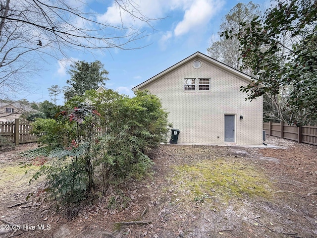 view of side of property with fence and brick siding