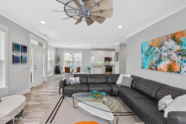 living room featuring ceiling fan, light hardwood / wood-style floors, crown molding, and sink