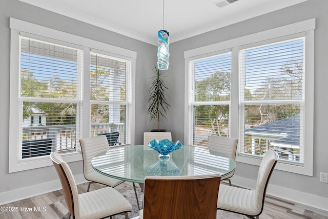 dining space featuring crown molding, light hardwood / wood-style flooring, and a healthy amount of sunlight