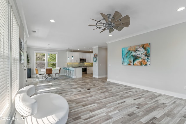106 SE 36th St, Oak Island, NC 28465 - living room with light wood-type flooring, crown molding, recessed lighting, ceiling fan, and baseboards