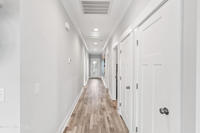 hallway with ornamental molding and light hardwood / wood-style flooring