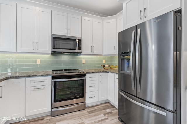 106 SE 36th St, Oak Island, NC 28465 - kitchen featuring appliances with stainless steel finishes, white cabinetry, dark stone countertops, and light wood-style floors
