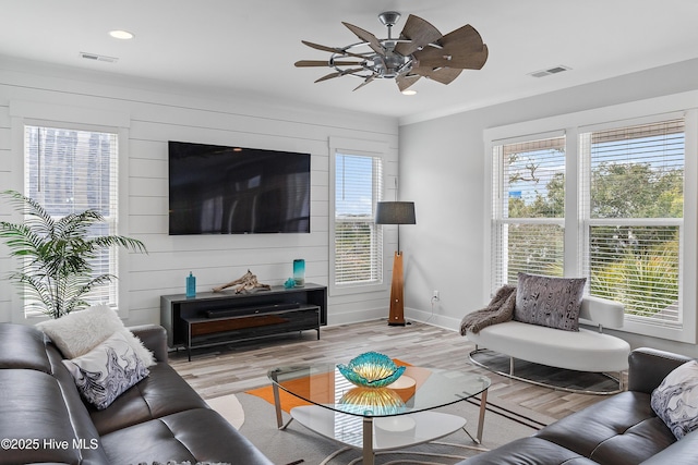 living room featuring crown molding, ceiling fan, and light hardwood / wood-style flooring