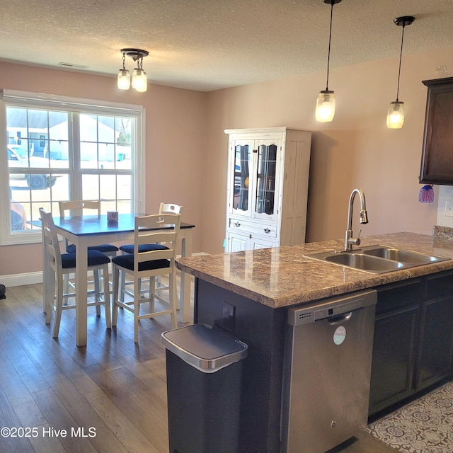 kitchen with decorative light fixtures, sink, light wood-type flooring, stainless steel dishwasher, and a textured ceiling