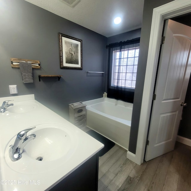 bathroom with a tub to relax in, hardwood / wood-style floors, and vanity