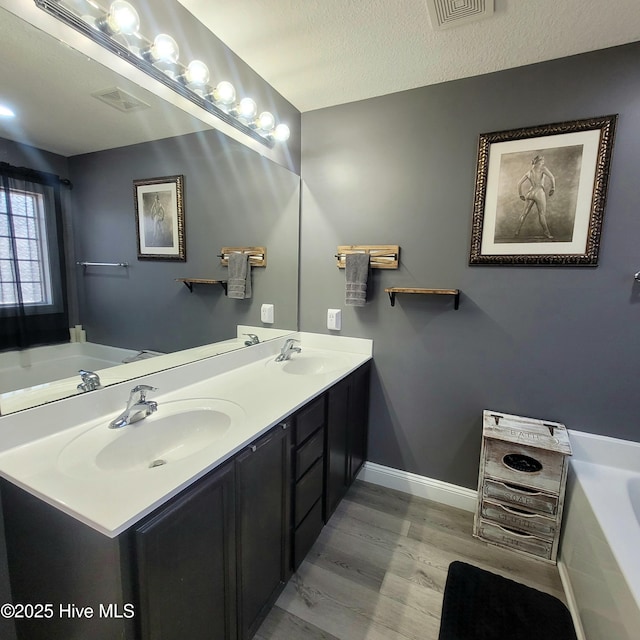 bathroom featuring hardwood / wood-style flooring, vanity, a textured ceiling, and a washtub