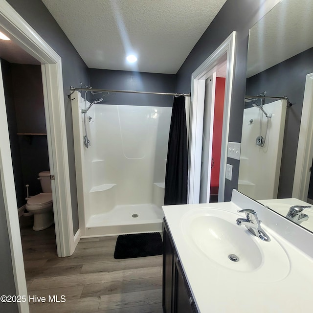 bathroom featuring a textured ceiling, wood-type flooring, toilet, and a shower with shower curtain