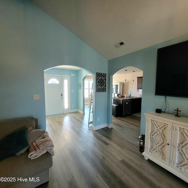 living room featuring high vaulted ceiling and wood-type flooring