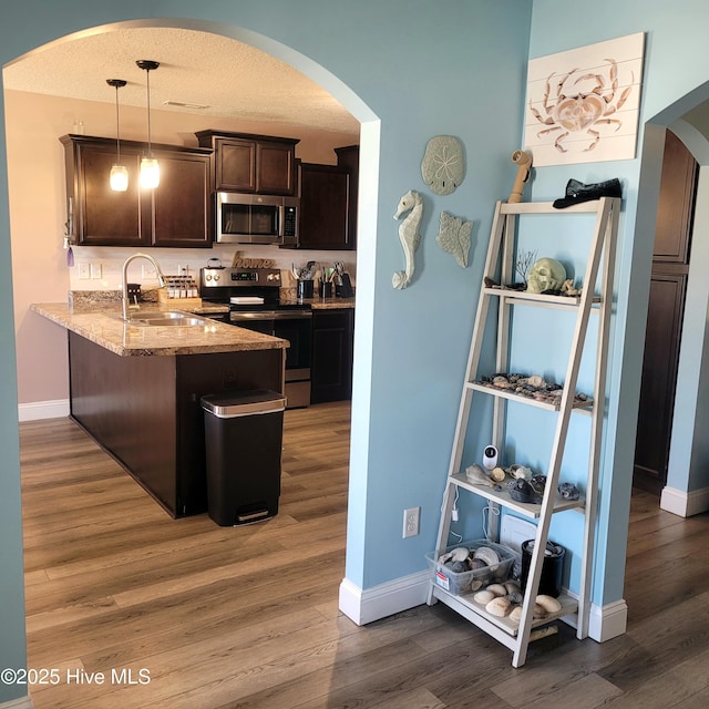 kitchen featuring sink, decorative light fixtures, appliances with stainless steel finishes, dark hardwood / wood-style floors, and kitchen peninsula