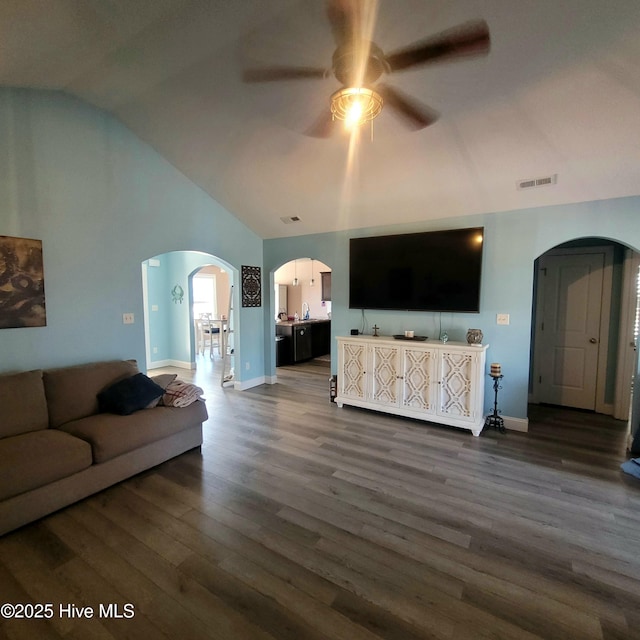 living room featuring dark wood-type flooring, ceiling fan, and vaulted ceiling