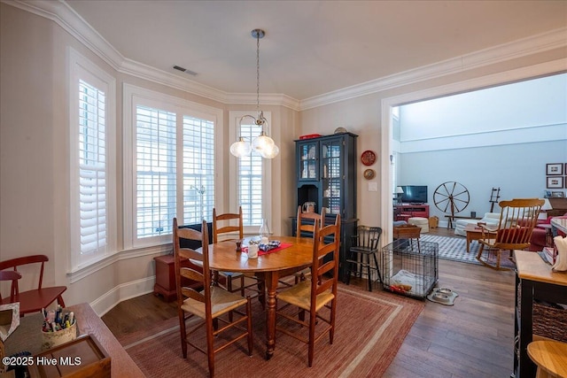 dining area with a notable chandelier, wood finished floors, visible vents, and ornamental molding