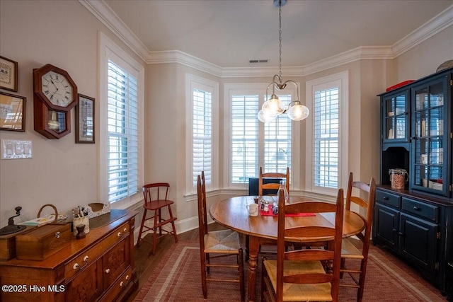 dining room with dark wood finished floors, plenty of natural light, visible vents, and ornamental molding