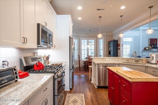 kitchen with visible vents, a sink, ornamental molding, stainless steel appliances, and wood counters