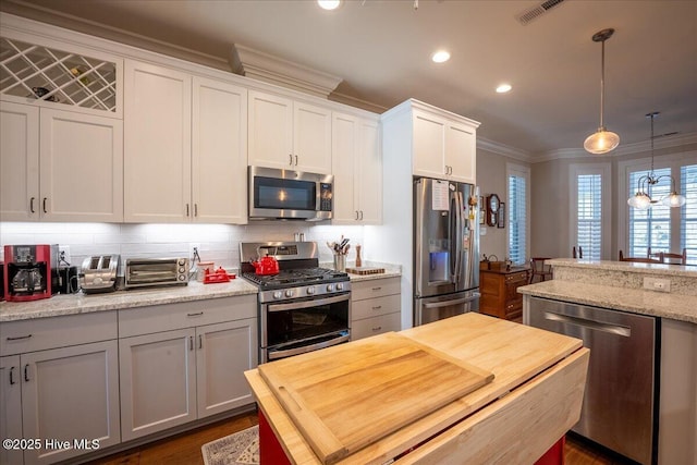 kitchen with visible vents, stainless steel appliances, white cabinetry, crown molding, and backsplash