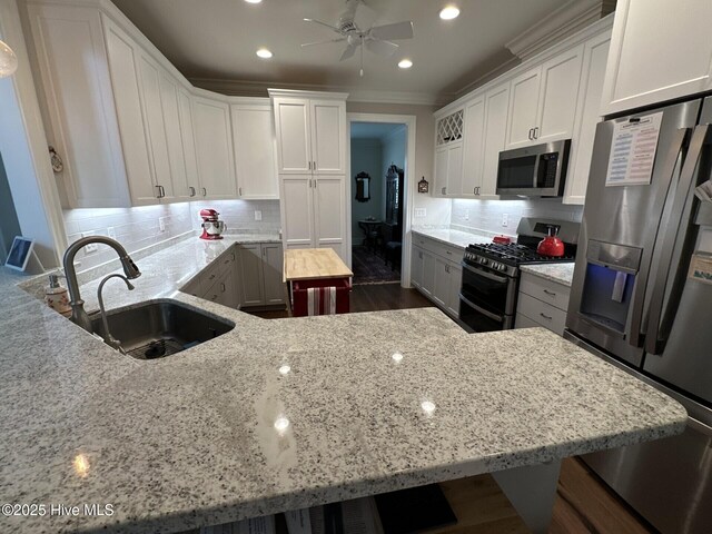 kitchen with a breakfast bar, ornamental molding, white cabinetry, freestanding refrigerator, and a peninsula